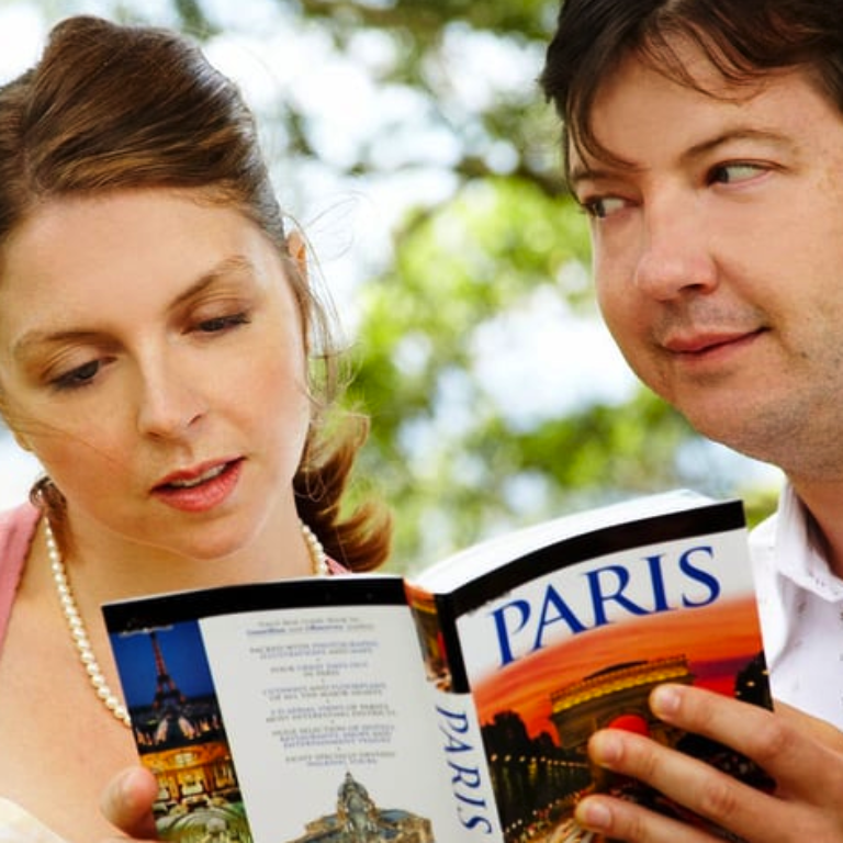 Man looking at a Paris holiday brochure next to a woman